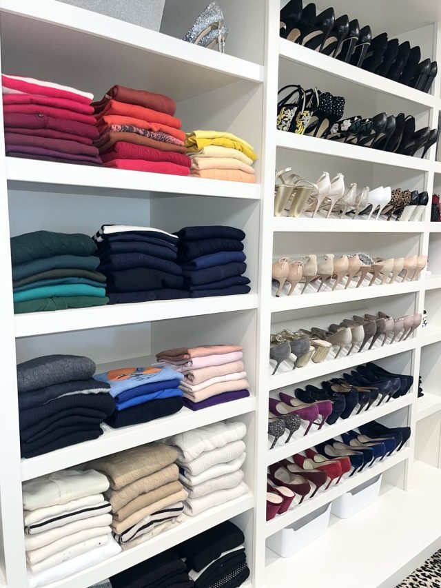 Folded sweaters on white shelves beside a full-height rack of shoes