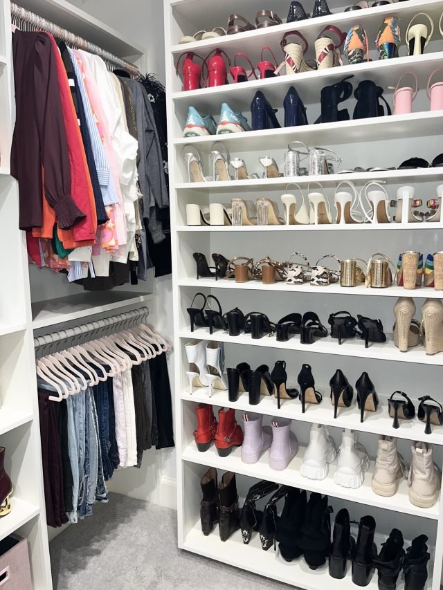 Full-height shoe shelving beside racks of hanging clothes in a white walk-in