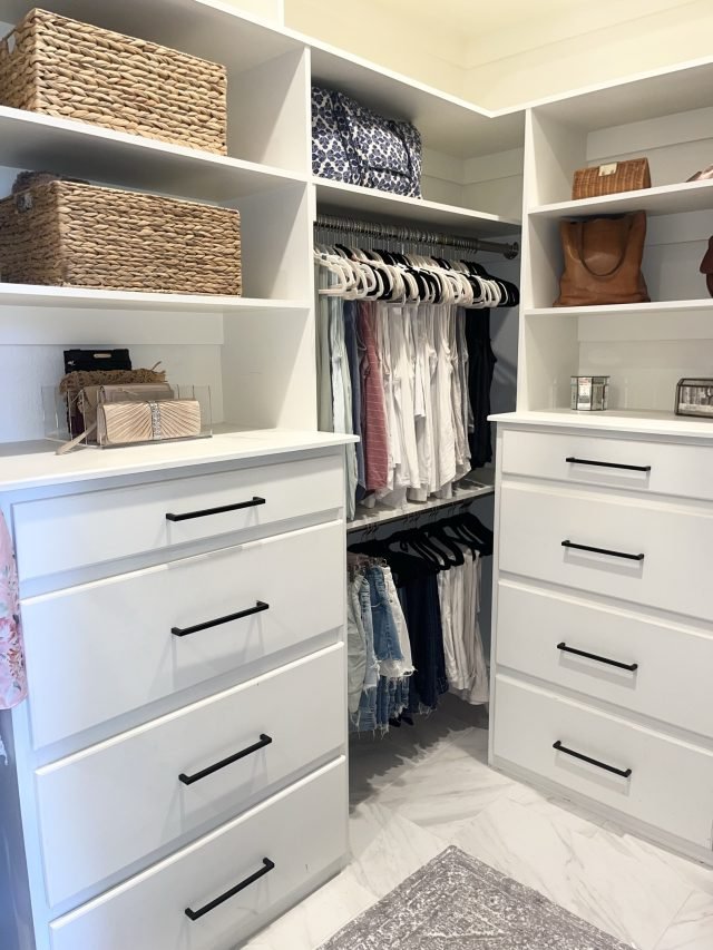 A white walk-in with a central drawer island, woven baskets above and hanging rods