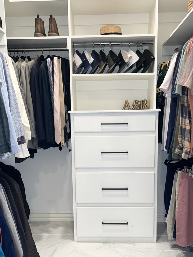 A his-and-hers closet with a monogrammed drawer tower between two hanging sides
