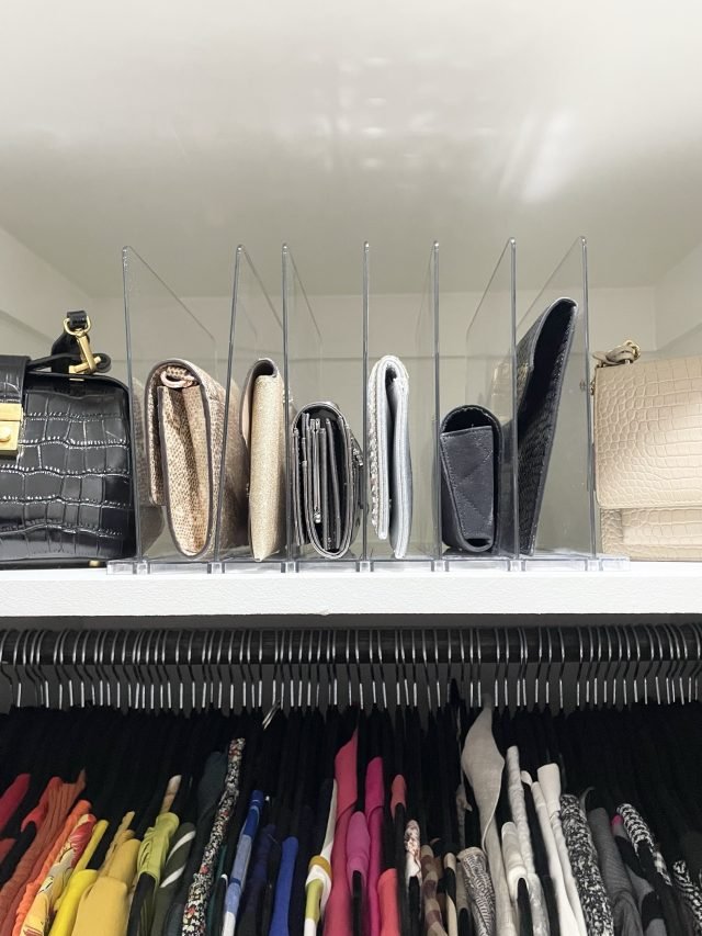 Clutches and small bags standing upright between shelf dividers above two hanging rods