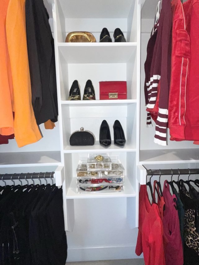 Handbags and heels shelved between racks of black pants and red tops