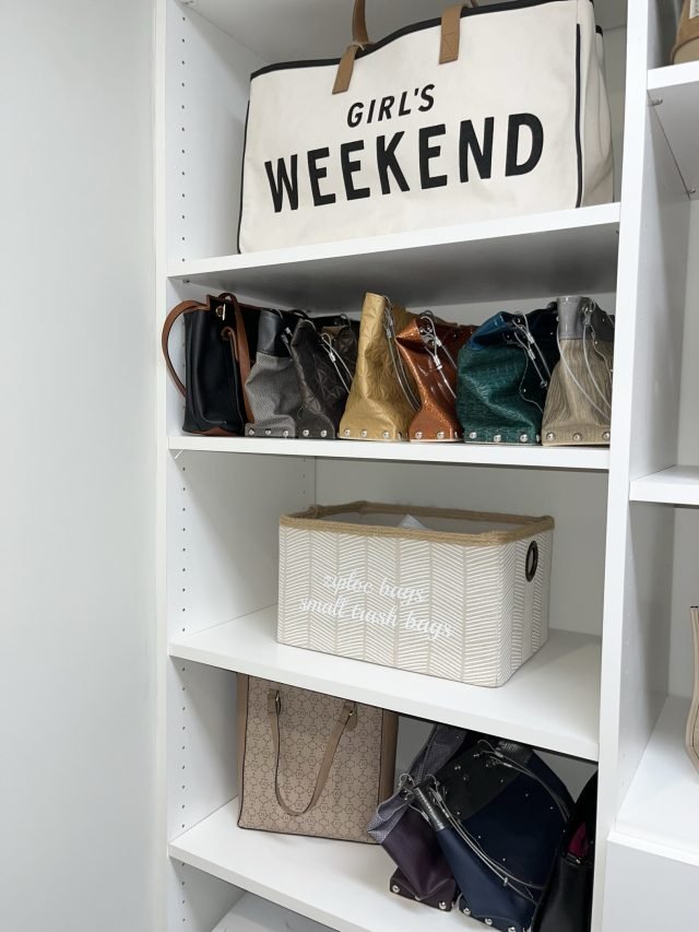Handbags upright between shelf dividers with a canvas weekend bag above