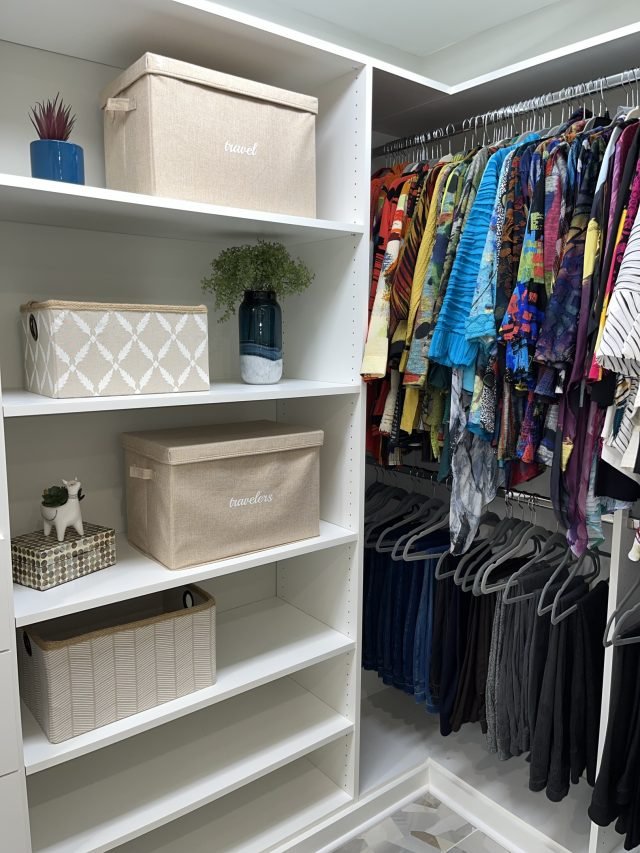 Labeled fabric bins on white shelving beside a row of hanging patterned clothing