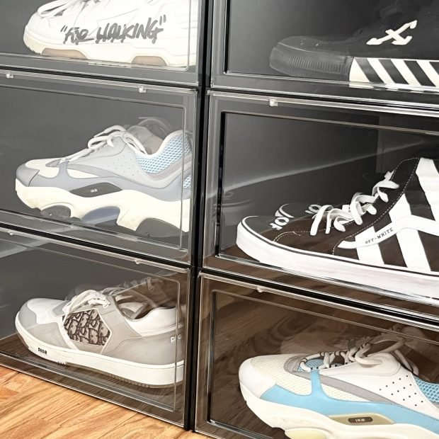 Trainers displayed in clear drop-front boxes on a wood floor