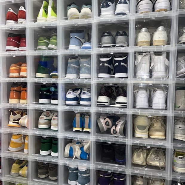 A full wall of sneakers in clear stacking boxes, sorted by color