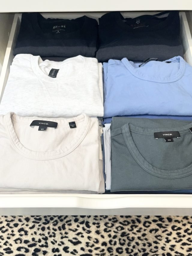 Folded sweaters and tees stacked in matched pairs on a closet shelf