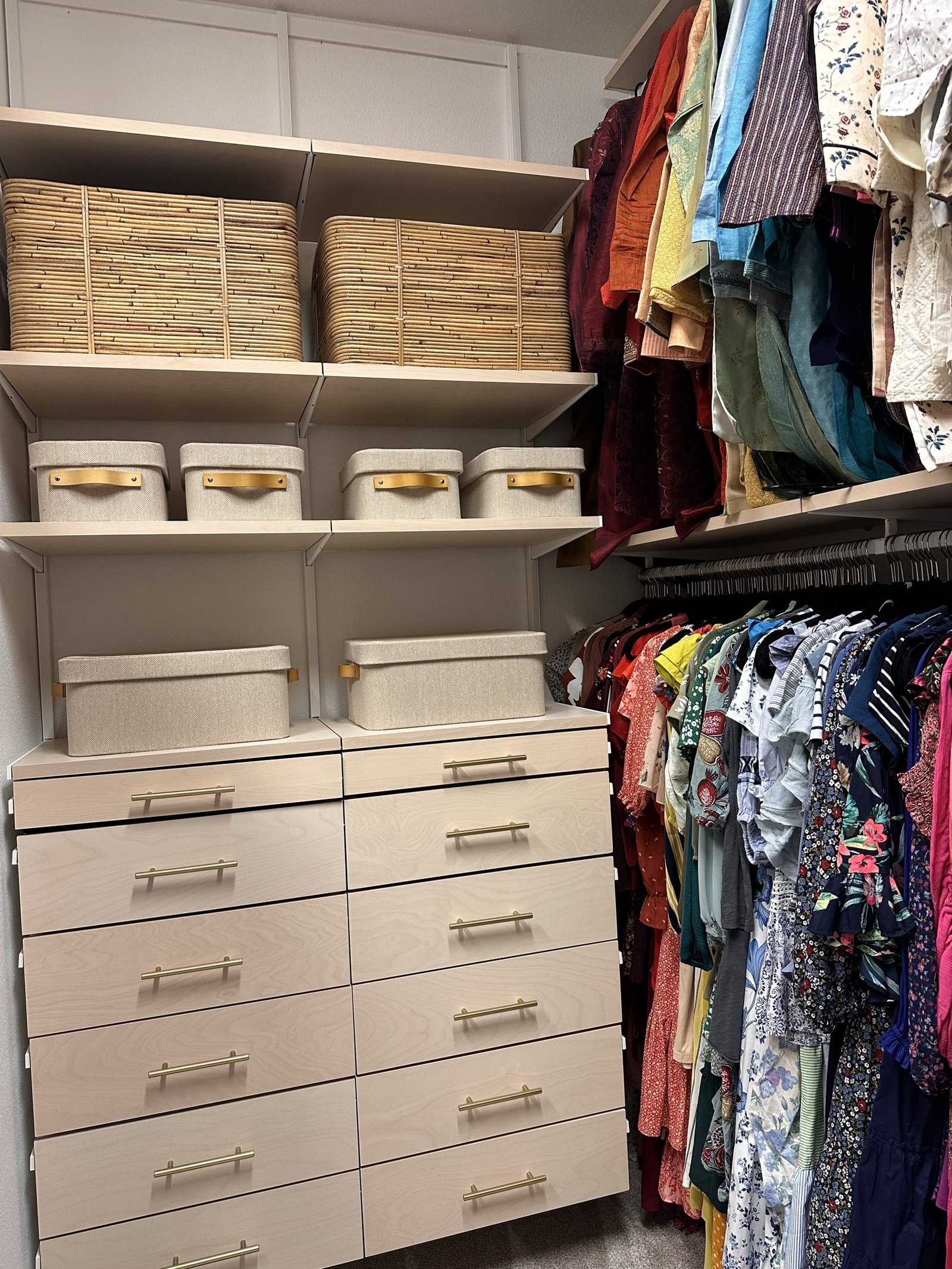 A closet with baskets stored above the rail, drawers below and clothes hung by category