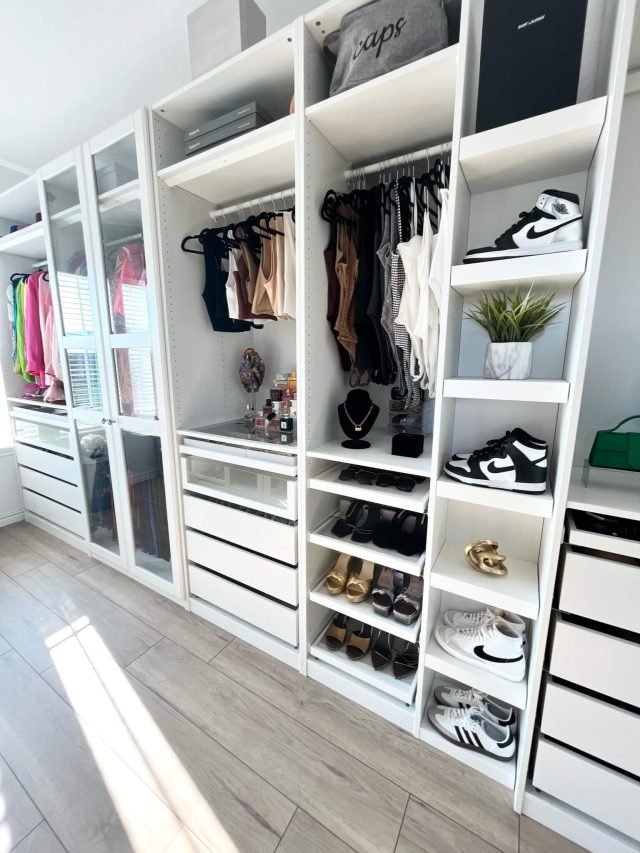 Professional organizer arranging clothing on hanging rods in a newly organized walk-in closet