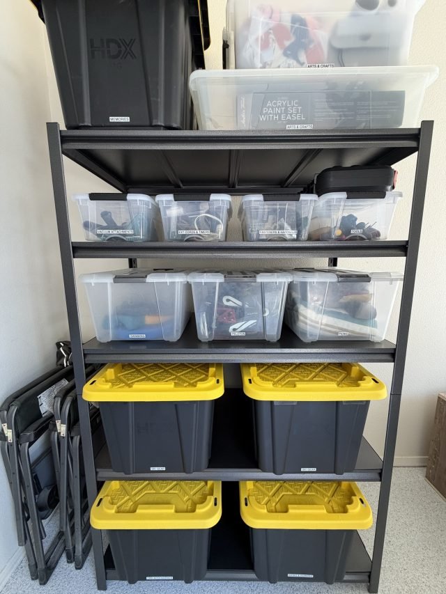 A steel garage rack holding clear bins above labeled black-and-yellow totes