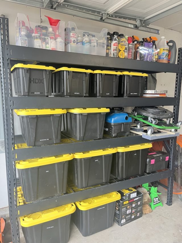 Steel garage shelving with labeled totes below and clear bins on top