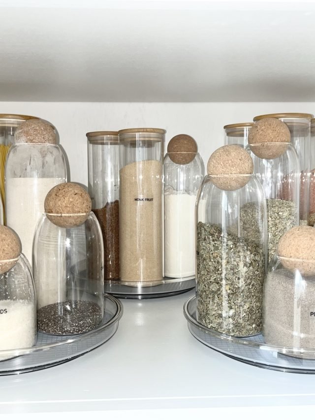 Glass canisters of flour, sugar and spices on turntables in a pantry cabinet
