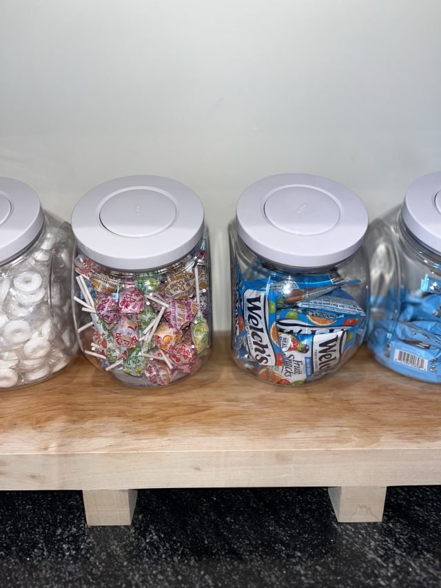 Glass jars of candy lined up on a butcher-block counter