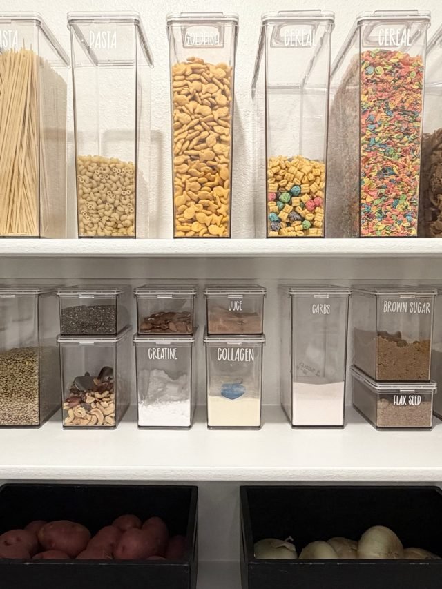 Dry goods in labeled clear canisters above bins and two produce trays