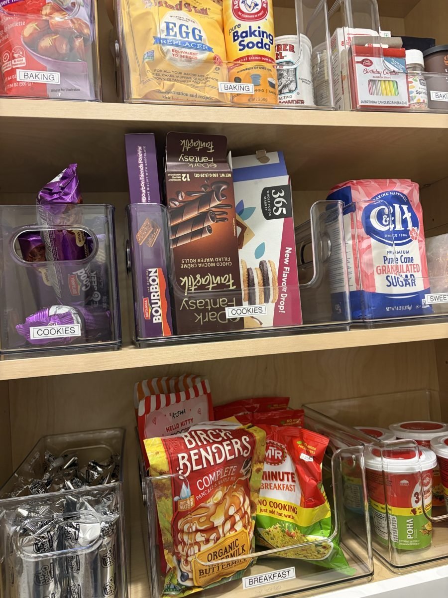 A baking cabinet with clear bins for sprinkles, sugar and snack bags
