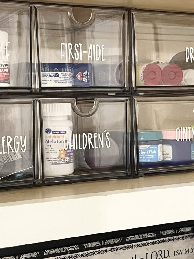A medicine cabinet with clear bins labeled pain relief, first aid and prescriptions