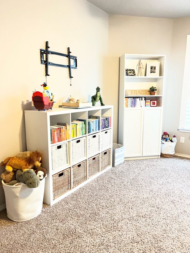 A playroom with a cube bookshelf, soft toys in a basket and books shelved