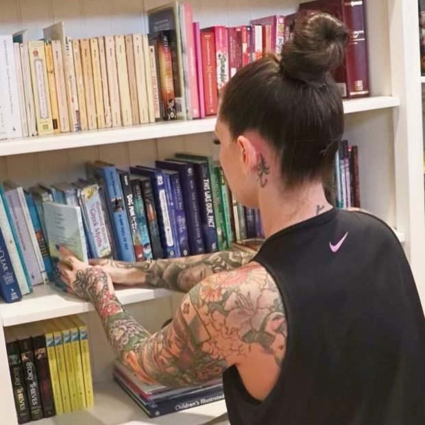 Ashley Matteson shelving books by size and color on a client's built-in